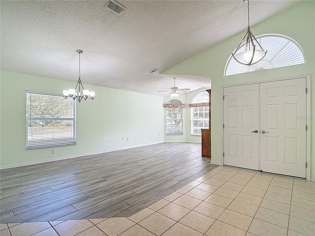 280 Quane Avenue Spring Hill, FL 34609 - Photo 11 of 62 an empty room with wooden floor chandelier fan and windows