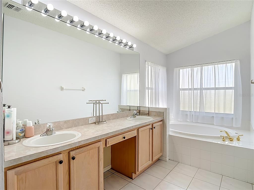 280 Quane Avenue Spring Hill, FL 34609 - Photo 30 of 62 a bathroom with a granite countertop bathtub a sink and a large mirror