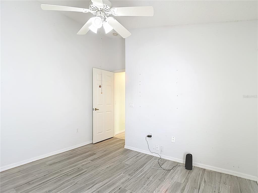 280 Quane Avenue Spring Hill, FL 34609 - Photo 39 of 62 a view of an empty room with wooden floor and a ceiling fan
