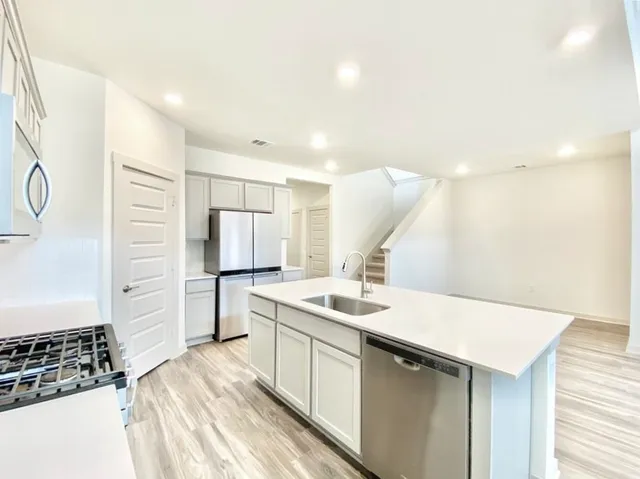 a view of a kitchen with kitchen island stainless steel appliances counter space and a window