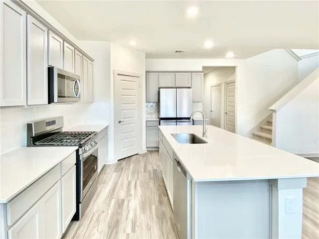 a kitchen with stainless steel appliances a stove a sink a microwave and cabinets