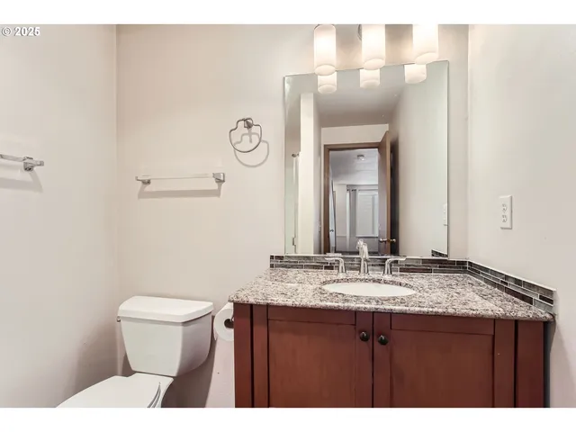 a bathroom with a granite countertop sink toilet and mirror
