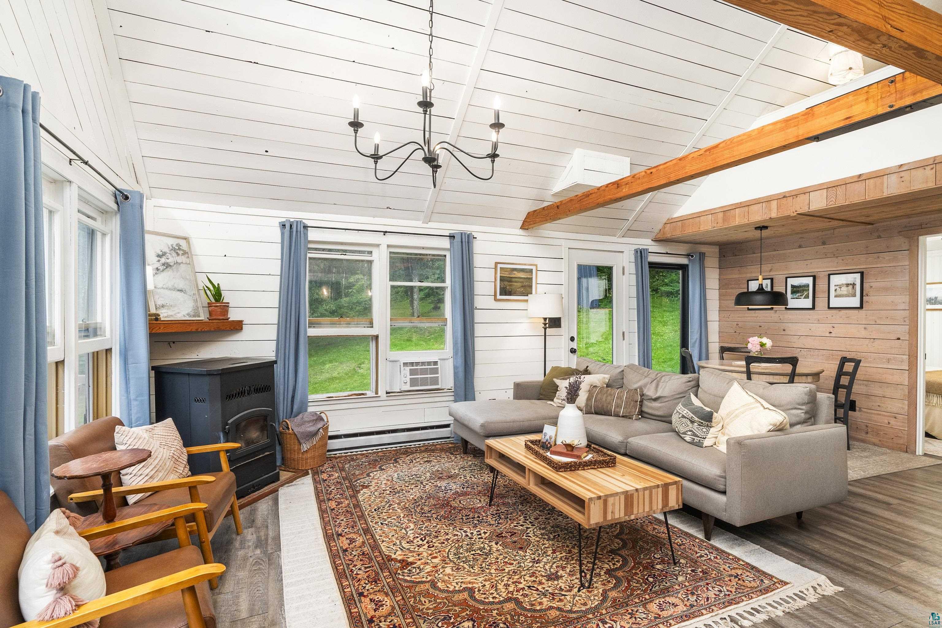 6345 Smith Lake Road Barnes, WI 54873 - Photo 13 of 50 Living room with wood-type flooring, a wood stove, a baseboard heating unit, vaulted ceiling, and wood walls