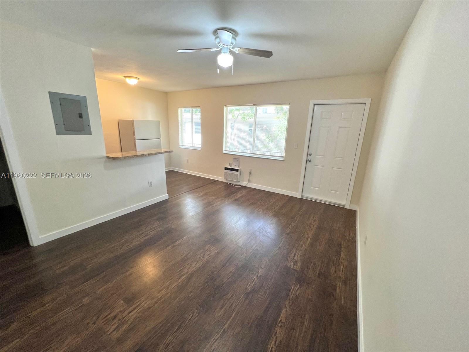 an empty room with wooden floor chandelier fan and windows