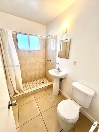 a white toilet sitting next to a bathroom sink and a shower