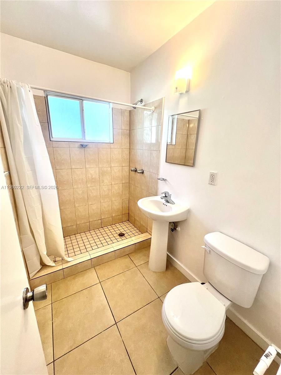 692 Northeast 85th Street, Unit 6 Miami, FL 33138 - Photo 6 of 6 a white toilet sitting next to a bathroom sink and a shower