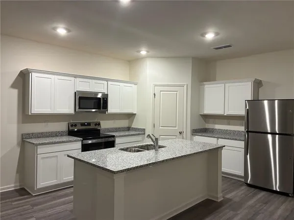 a kitchen with kitchen island granite countertop a sink and a stove top oven with wooden floor