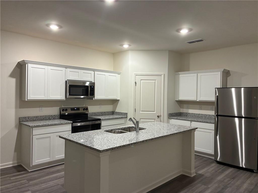 54 Rowlett Place Winder, GA 30680 - Photo 1 of 1 a kitchen with kitchen island granite countertop a sink and a stove top oven with wooden floor