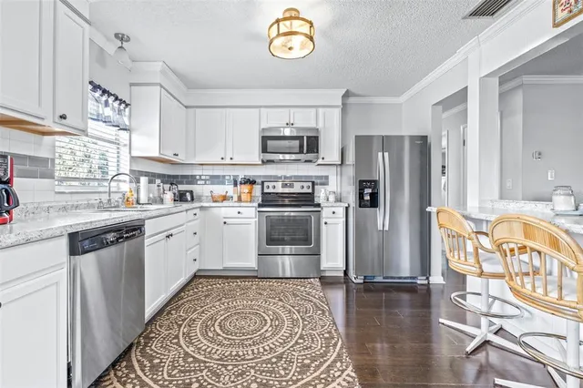 a kitchen with stainless steel appliances granite countertop a refrigerator oven stove a sink and a dining table with wooden floor