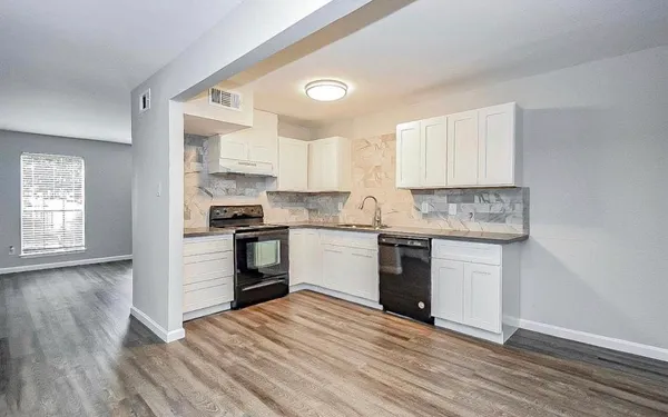 a kitchen with granite countertop wooden floors stainless steel appliances and sink