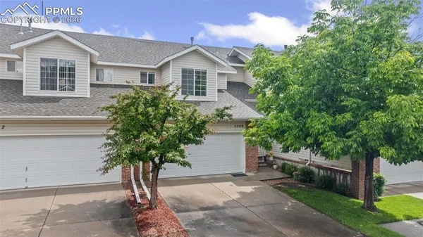 a front view of a house with a yard and trees