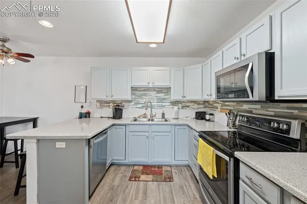 a kitchen with stainless steel appliances a sink cabinets and wooden floor