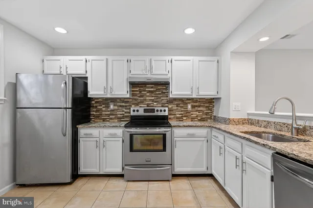 a kitchen with a refrigerator sink and cabinets