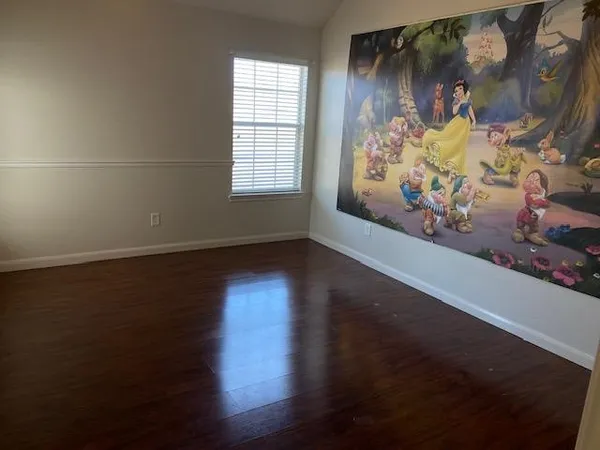 en empty room with window and wooden floor