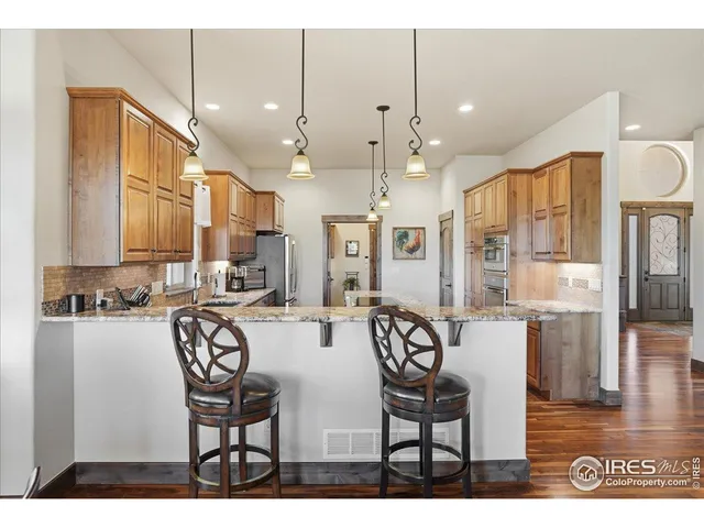 a view of a dining room and livingroom with furniture wooden floor a rug a fireplace and a chandelier