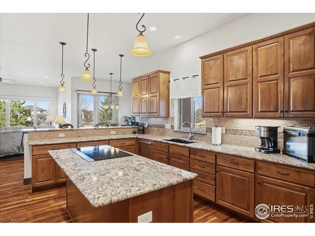 a kitchen with stainless steel appliances granite countertop wooden cabinets a stove a sink and a wooden floors