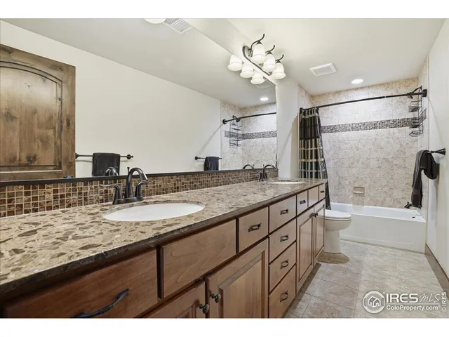 a bathroom with a granite countertop sink a toilet a mirror and shower