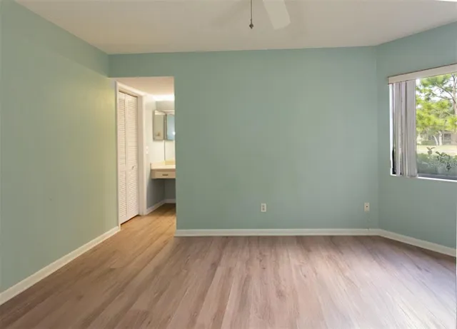 an empty room with wooden floor and windows