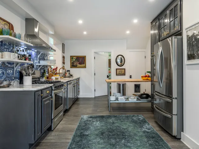 a kitchen with stainless steel appliances kitchen island granite countertop a refrigerator a stove top oven and a sink