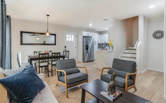a living room with furniture kitchen view and a wooden floor