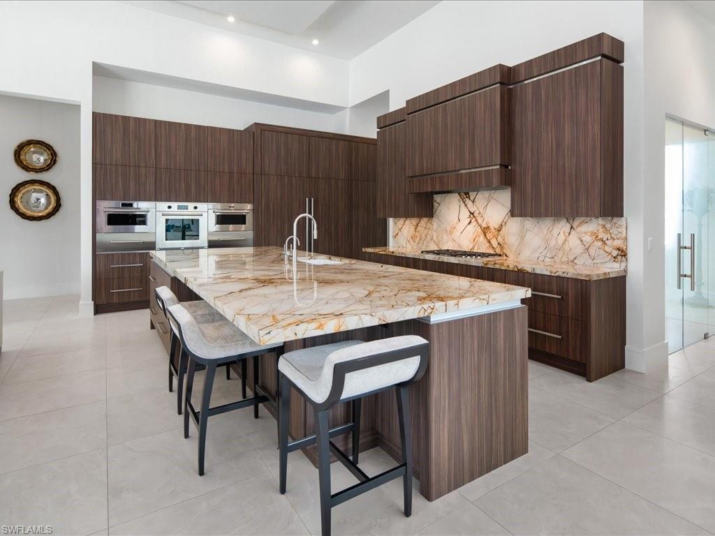 172 Center Street Naples, FL 34108 - Photo 16 of 50 a kitchen with granite countertop a table chairs stove and cabinets