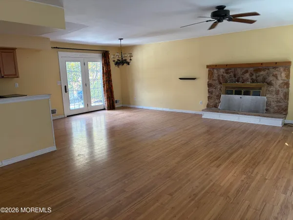 an empty room with wooden floor fireplace and windows