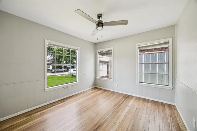 a view of an empty room with a window and wooden floor
