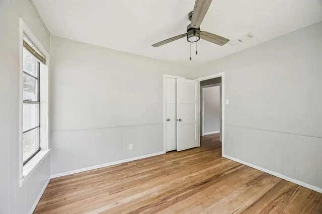 a view of empty room with wooden floor and fan