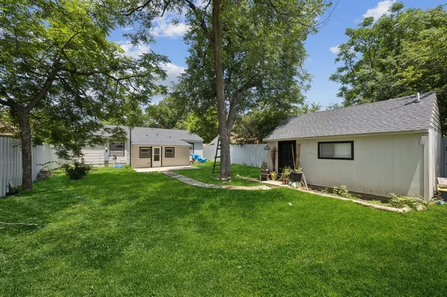 a view of a house with a big yard potted plants and a large tree