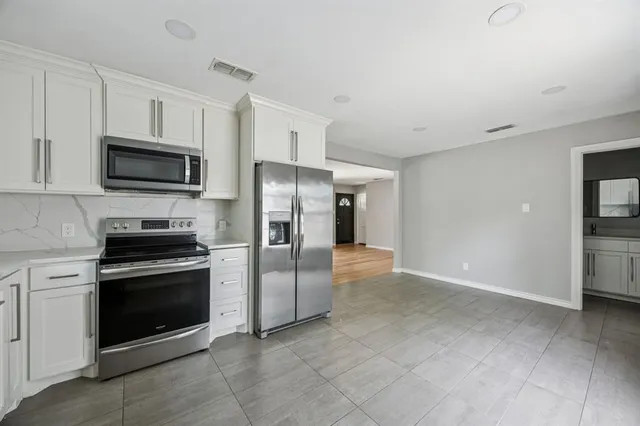 a kitchen with stainless steel appliances granite countertop a refrigerator and a stove top oven