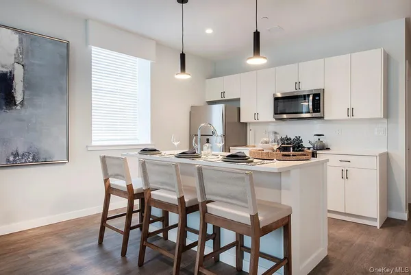 a kitchen with stainless steel appliances granite countertop a stove a sink a microwave a refrigerator a dining table and chairs with wooden floor