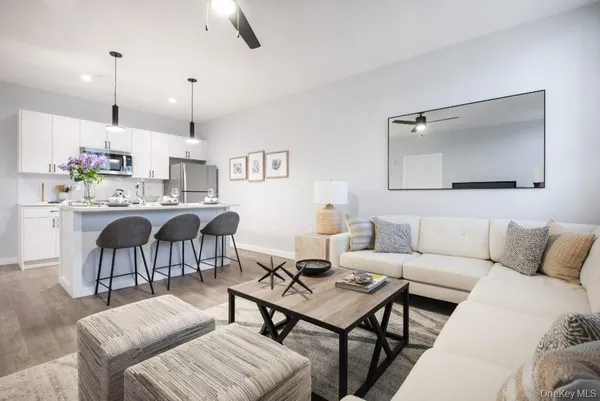 a living room with furniture kitchen view and a wooden floor