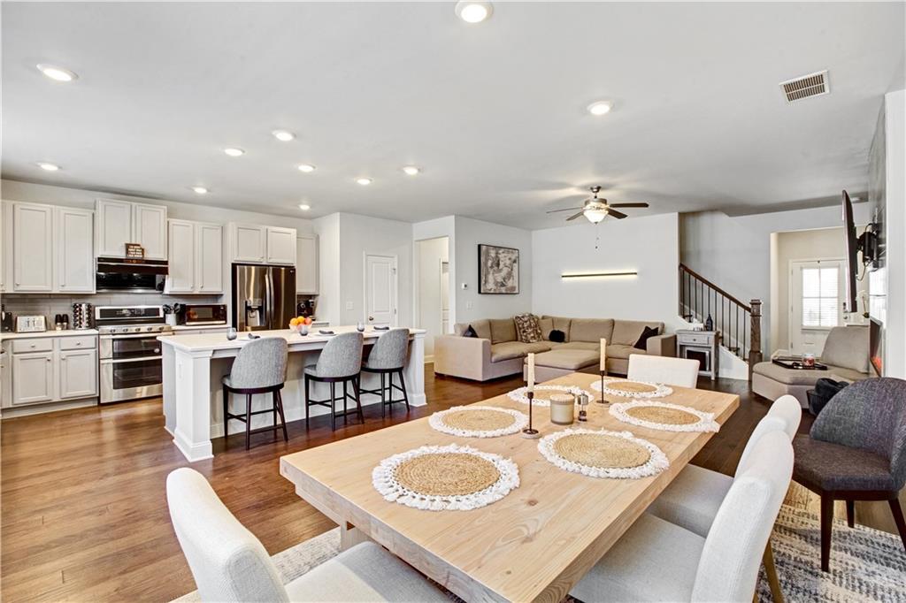 3434 Senna Road Duluth, GA 30096 - Photo 12 of 39 a living room with stainless steel appliances kitchen island granite countertop a dining table chairs refrigerator sink and cabinets