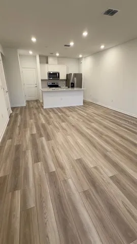 a view of large kitchen with kitchen island sink and wooden floor