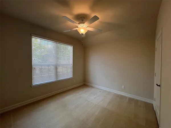 an empty room with a chandelier fan and windows