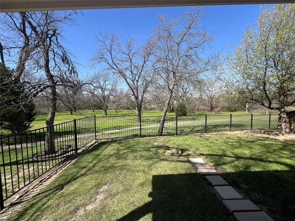 a view of a trees in a yard with a wooden fence