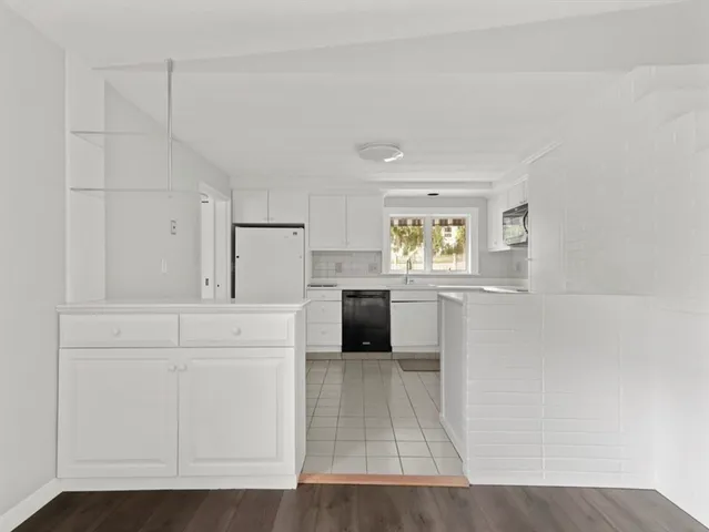 a kitchen with white cabinets and window