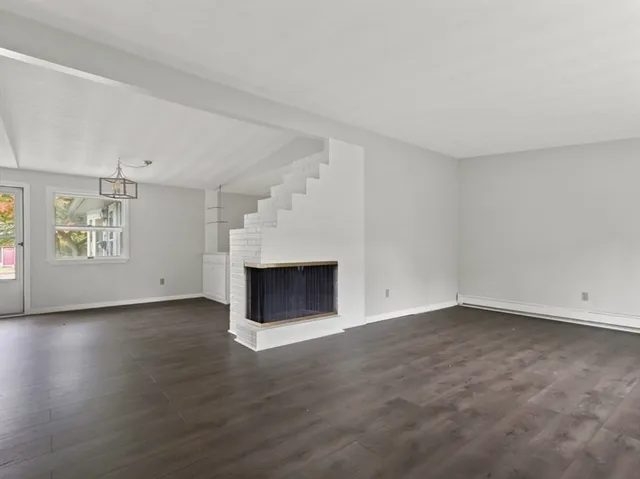 an empty room with wooden floor fireplace and windows