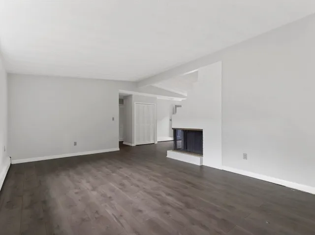 an empty room with wooden floor and fireplace