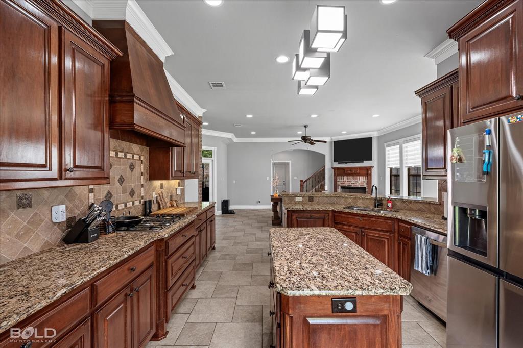 2220 Forest Hills Boulevard Haughton, LA 71037 - Photo 17 of 40 Spacious kitchen featuring dark wood cabinetry, granite countertops, a tiled backsplash, and stainless steel appliances