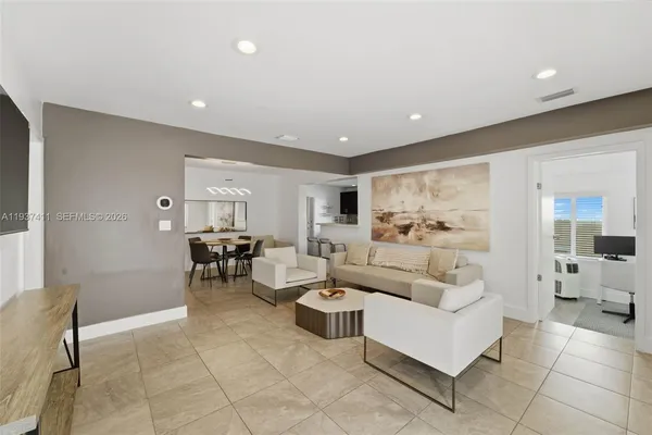a living room with couches and kitchen view with wooden floor