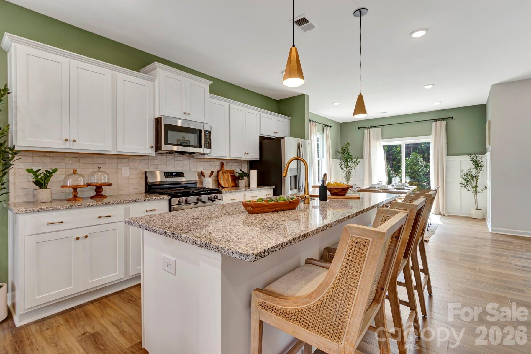 1452 Kate Cecil Way York, SC 29745 - Photo 7 of 27 a kitchen with stainless steel appliances granite countertop a stove a sink a microwave a refrigerator white cabinets and wooden floor