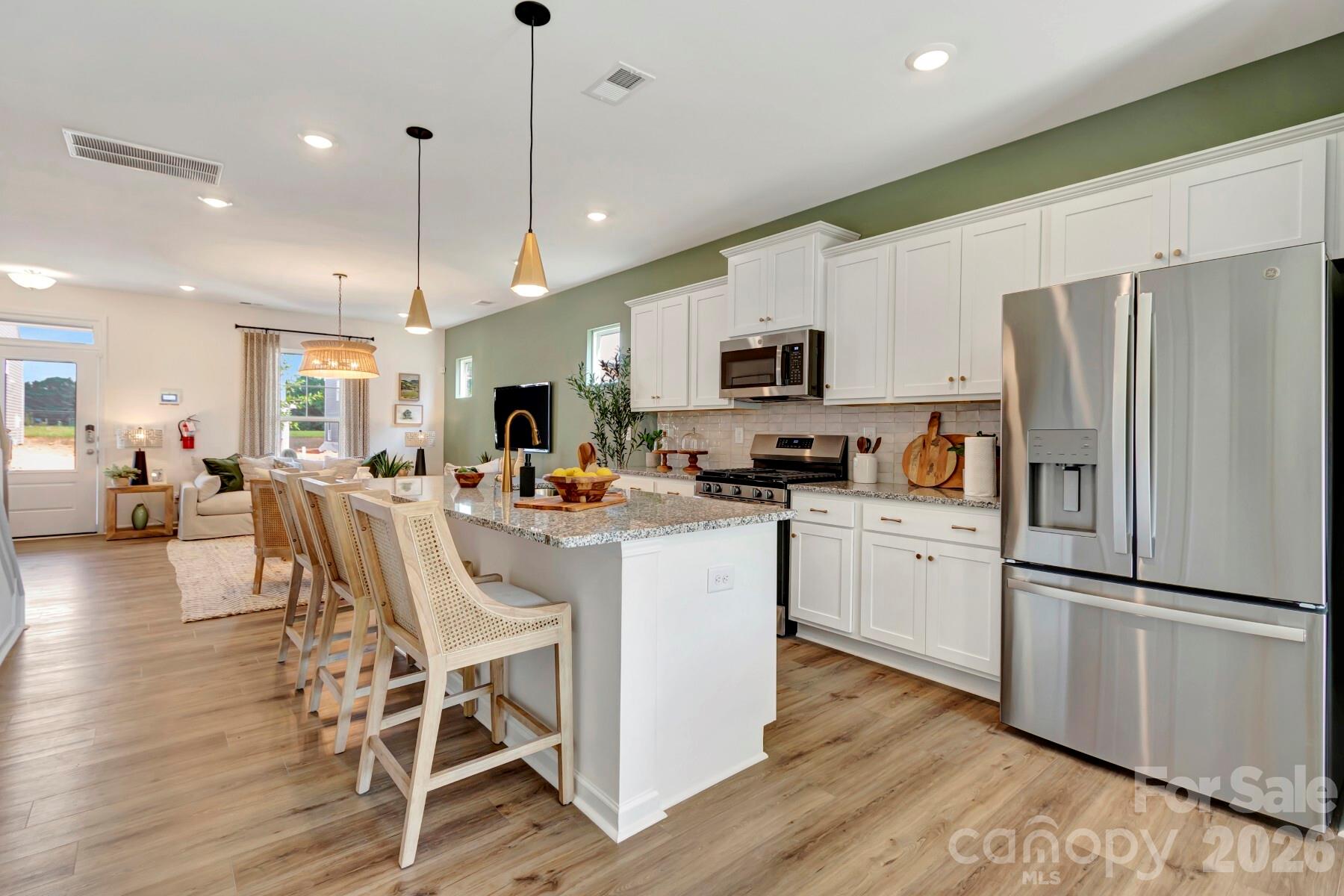 1452 Kate Cecil Way York, SC 29745 - Photo 10 of 27 a kitchen with stainless steel appliances a refrigerator a stove a sink a dining table and chairs with wooden floor