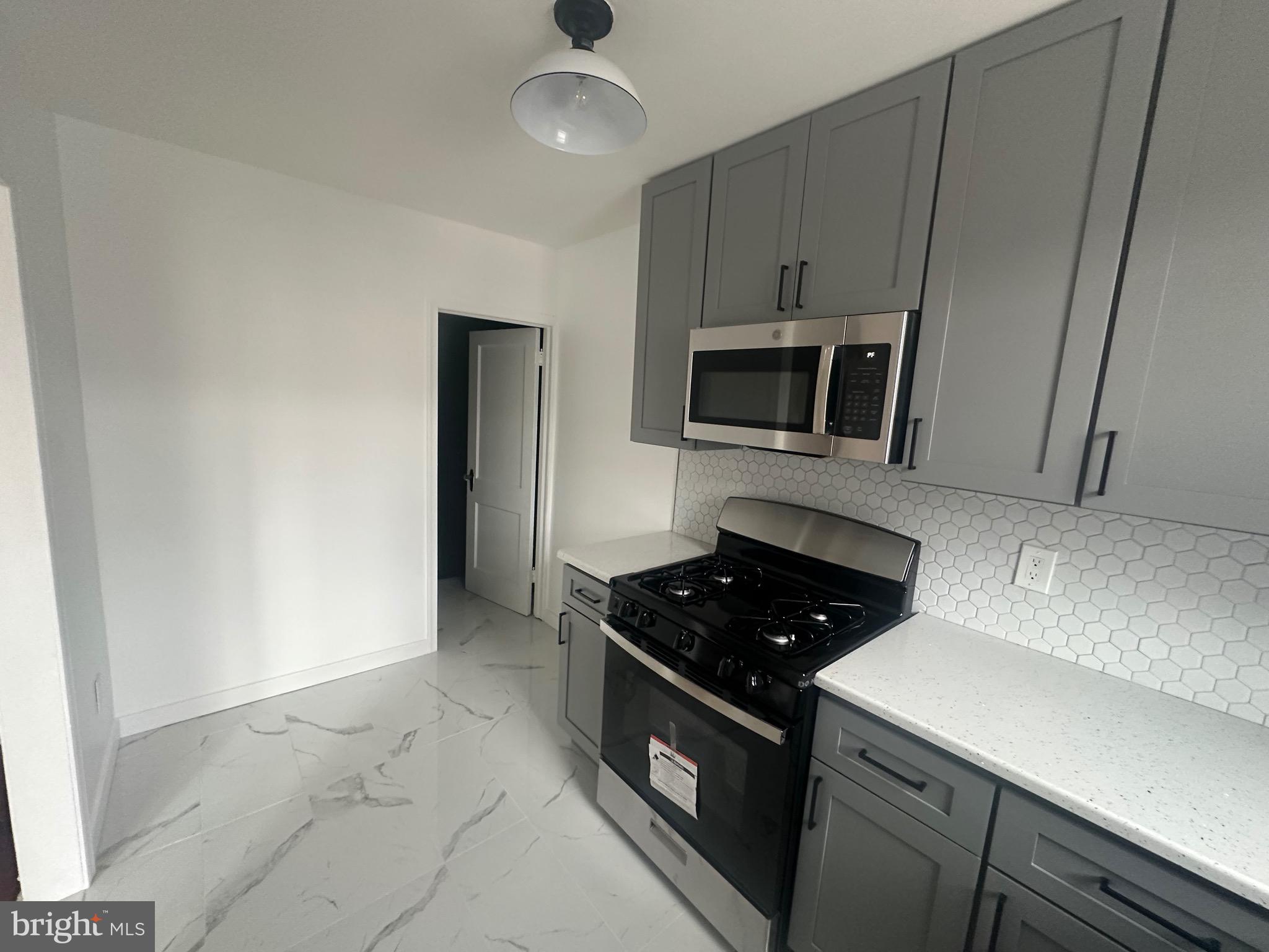 1440 Stirling Street Philadelphia, PA 19149 - Photo 15 of 18 a kitchen with granite countertop a stove and a microwave