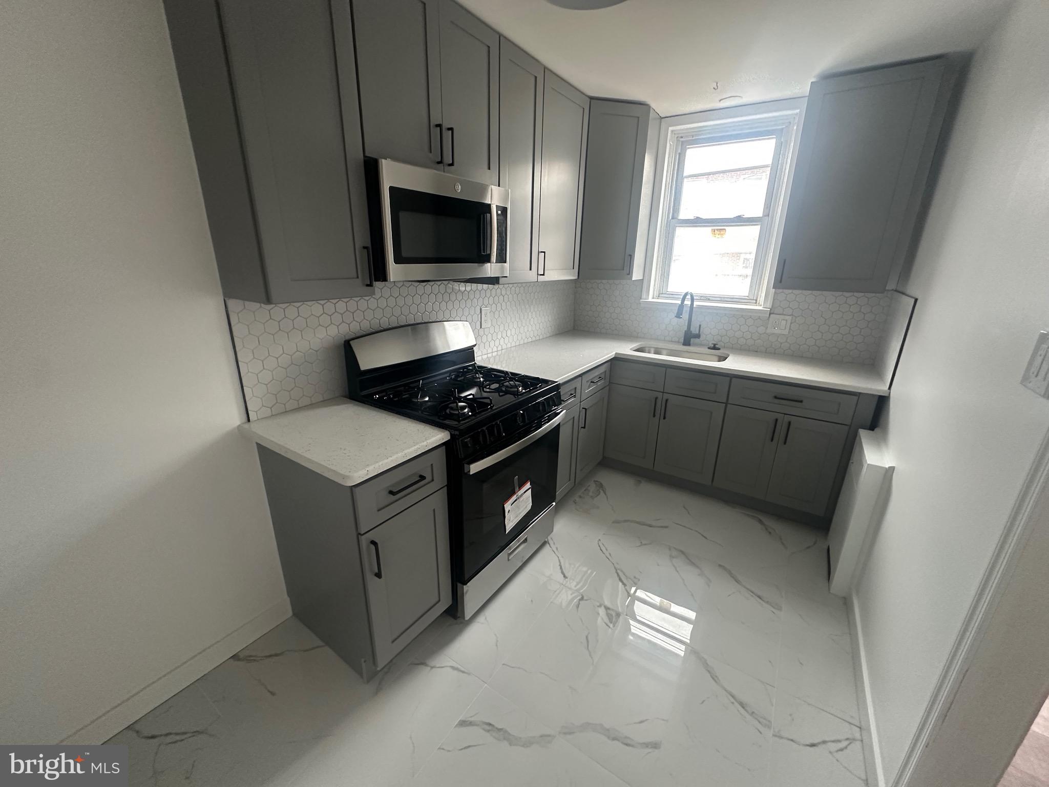 1440 Stirling Street Philadelphia, PA 19149 - Photo 17 of 18 a kitchen with stainless steel appliances granite countertop a sink stove and microwave
