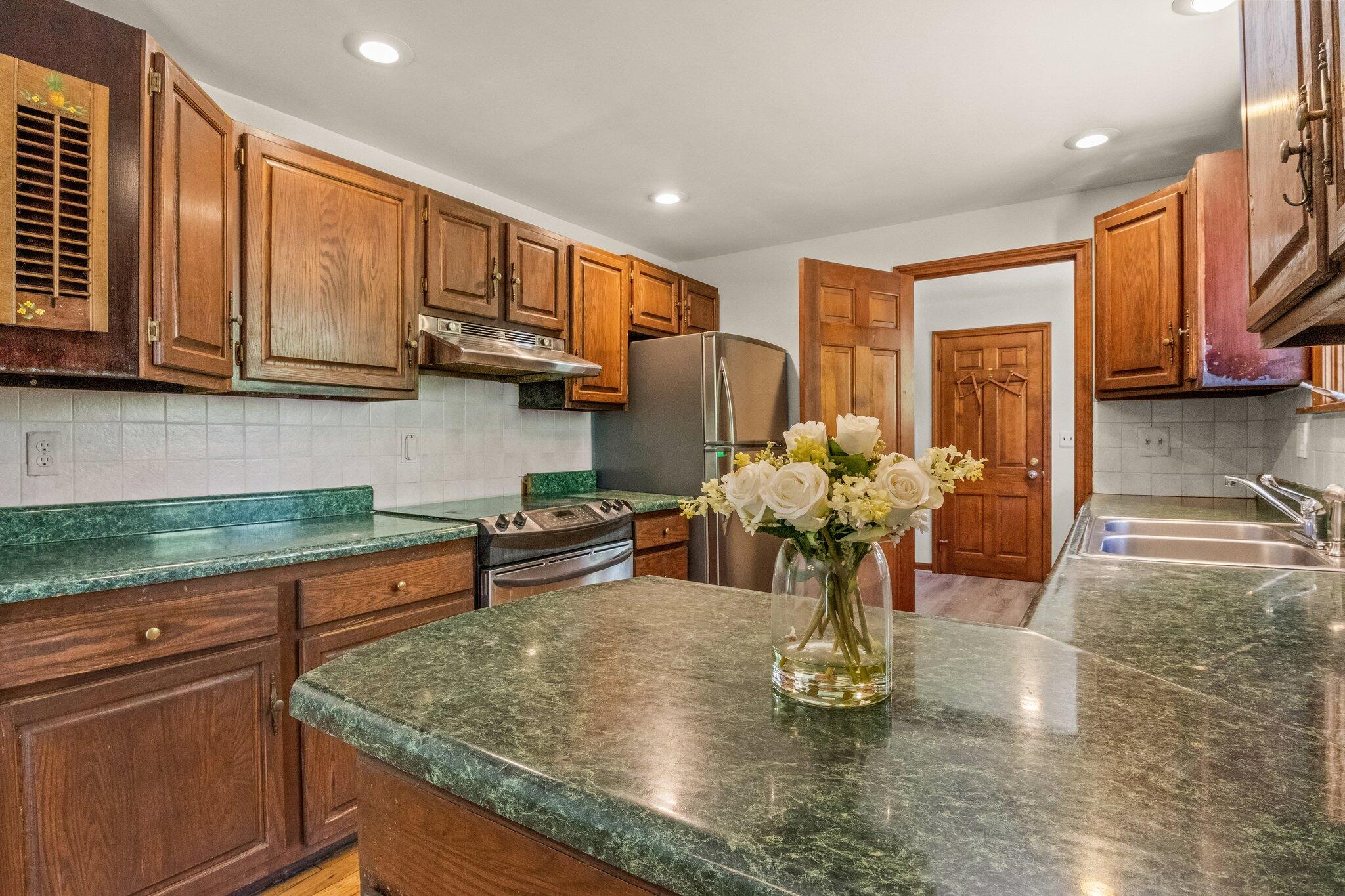 472 Elliott Road Centerville, MA 02632 - Photo 13 of 36 a kitchen with stainless steel appliances granite countertop a sink dishwasher a stove a refrigerator cabinets and a dining table with wooden floor
