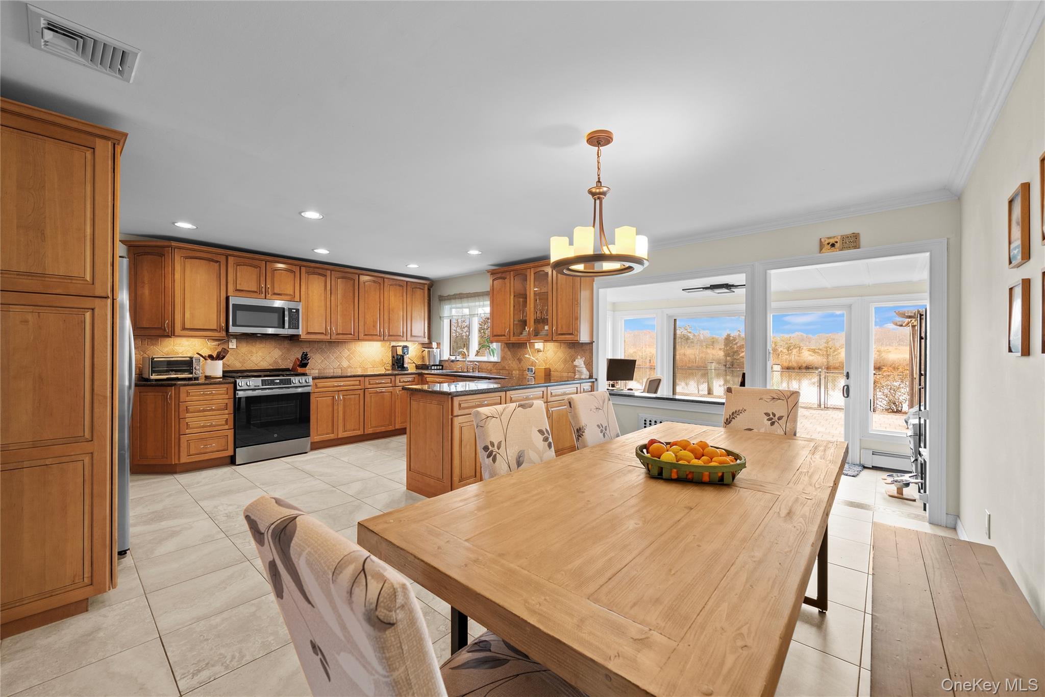625 Edgewater Road Oakdale, NY 11769 - Photo 11 of 49 Dining area featuring a chandelier, light tile patterned floors, recessed lighting, and crown molding