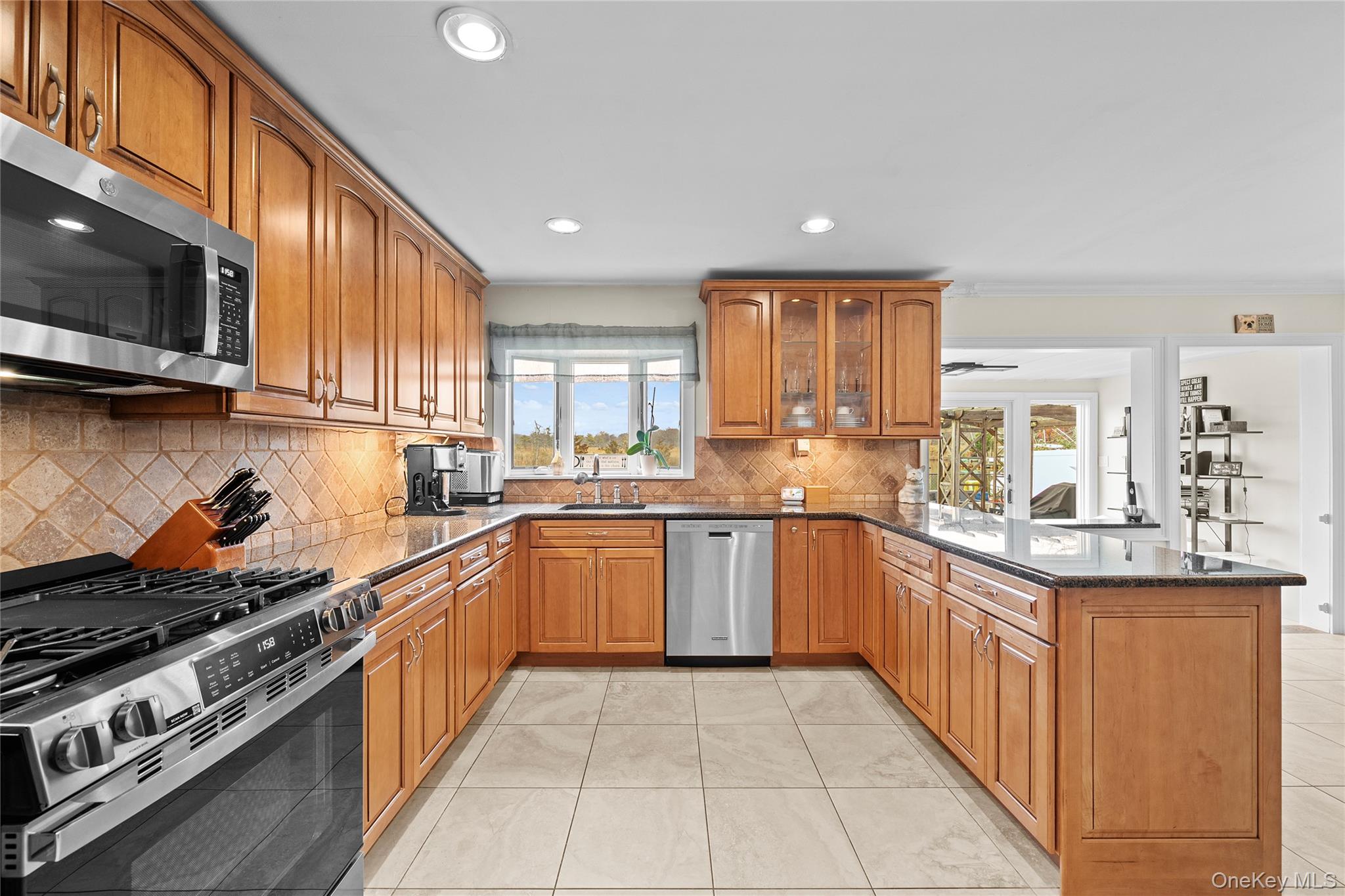 625 Edgewater Road Oakdale, NY 11769 - Photo 12 of 49 Kitchen with dark stone countertops, brown cabinetry, stainless steel appliances, recessed lighting, and a peninsula