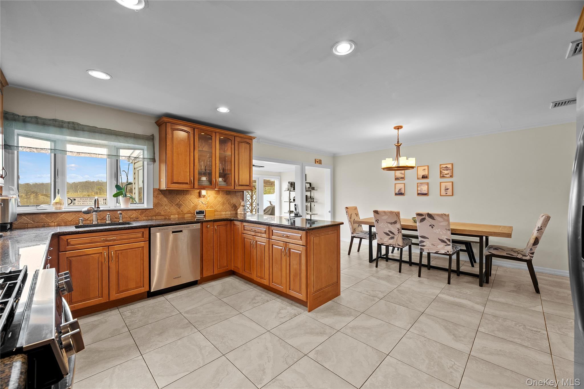 625 Edgewater Road Oakdale, NY 11769 - Photo 14 of 49 Kitchen featuring brown cabinets, backsplash, appliances with stainless steel finishes, dark stone counters, and glass insert cabinets