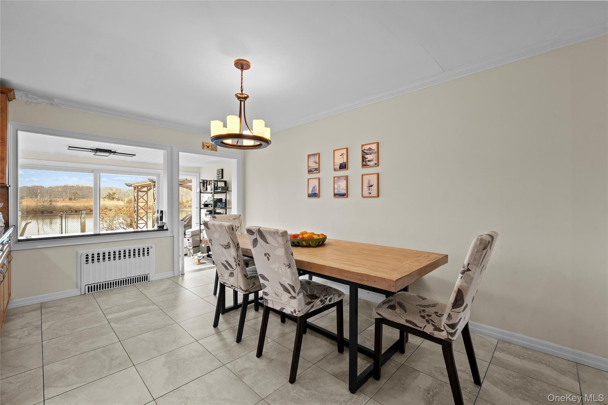 625 Edgewater Road Oakdale, NY 11769 - Photo 19 of 49 Dining space featuring radiator heating unit, ornamental molding, a chandelier, light tile patterned flooring, and a water view